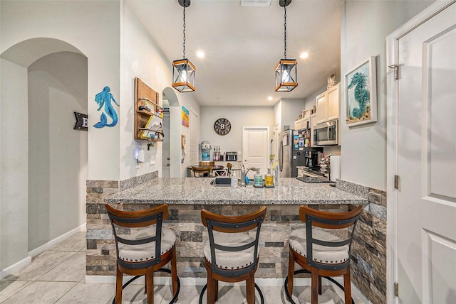 2844 Jacob Crossing Ln, Holiday, FL 34691 - kitchen featuring appliances with stainless steel finishes, a peninsula, recessed lighting, light stone countertops, and pendant lighting