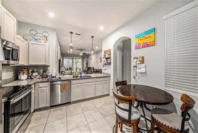 2844 Jacob Crossing Ln, Holiday, FL 34691 - kitchen featuring stainless steel appliances, stone counters, light tile patterned flooring, arched walkways, and recessed lighting