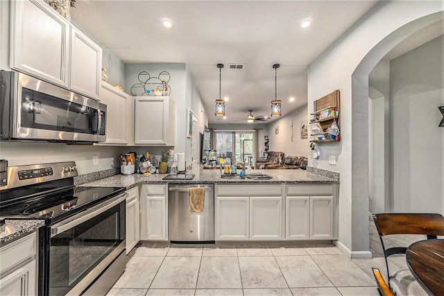 2844 Jacob Crossing Ln, Holiday, FL 34691 - kitchen with stainless steel appliances, a sink, arched walkways, a ceiling fan, and light stone countertops