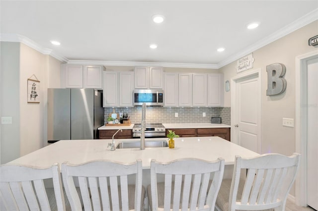 14716 Crescent Rock Dr, Wimauma, FL 33598 - kitchen with appliances with stainless steel finishes, light countertops, decorative backsplash, a sink, and a breakfast bar