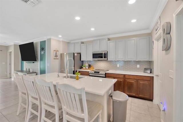 14716 Crescent Rock Dr, Wimauma, FL 33598 - kitchen with stainless steel appliances, light tile patterned flooring, tasteful backsplash, light countertops, and ornamental molding