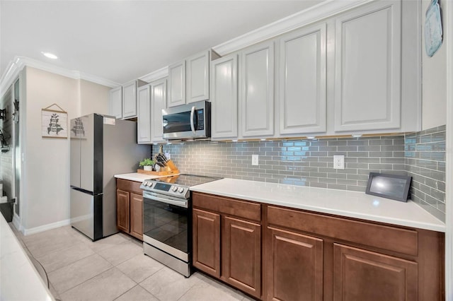 14716 Crescent Rock Dr, Wimauma, FL 33598 - kitchen with stainless steel appliances, light countertops, tasteful backsplash, light tile patterned floors, and baseboards