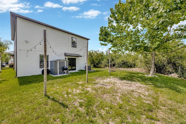 14716 Crescent Rock Dr, Wimauma, FL 33598 - back of house with central AC unit, a lawn, and stucco siding