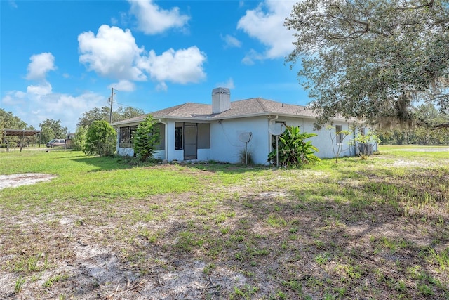 17023 Alderman Turner Rd, Wimauma, FL 33598 - rear view of property with a chimney, stucco siding, and a yard