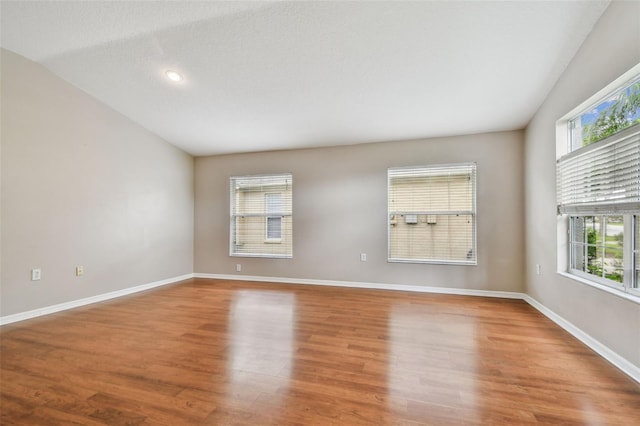 15709 Leatherleaf Ln, Land O Lakes, FL 34638 - empty room with healthy amount of natural light, wood finished floors, baseboards, recessed lighting, and vaulted ceiling