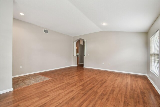 15709 Leatherleaf Ln, Land O Lakes, FL 34638 - unfurnished room with wood finished floors, arched walkways, baseboards, ornate columns, and vaulted ceiling