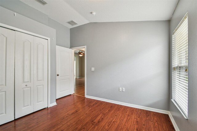 15709 Leatherleaf Ln, Land O Lakes, FL 34638 - unfurnished bedroom with dark wood finished floors, vaulted ceiling, multiple windows, and a closet