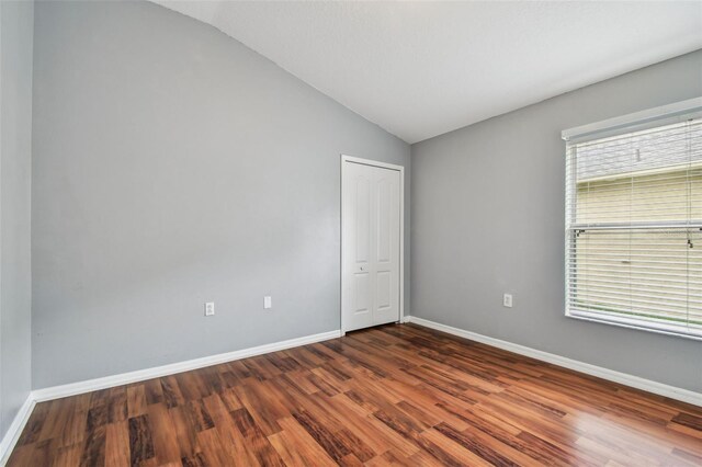15709 Leatherleaf Ln, Land O Lakes, FL 34638 - spare room featuring lofted ceiling, dark wood-style flooring, and baseboards