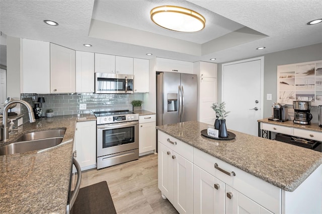 1621 Gulf Blvd Unit 407, Clearwater Beach, FL 33767 - kitchen with appliances with stainless steel finishes, a sink, a textured ceiling, decorative backsplash, and light wood-style flooring