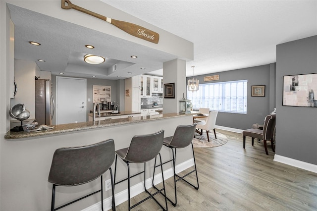 1621 Gulf Blvd Unit 407, Clearwater Beach, FL 33767 - kitchen with freestanding refrigerator, baseboards, a peninsula, a kitchen bar, and light wood-style flooring