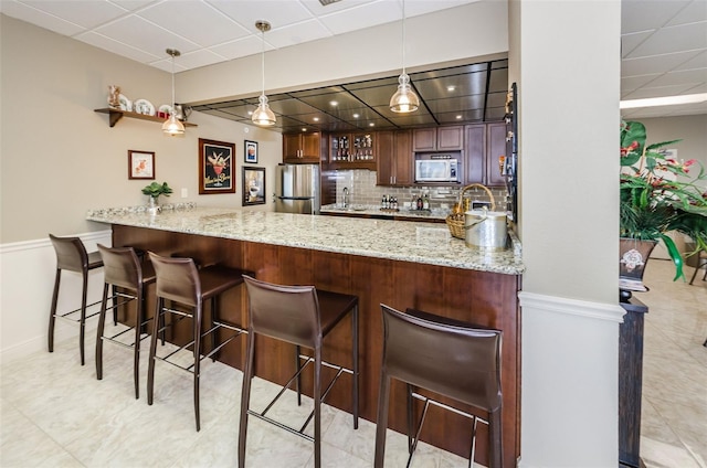 1621 Gulf Blvd Unit 407, Clearwater Beach, FL 33767 - kitchen with stainless steel appliances, a peninsula, a paneled ceiling, pendant lighting, and light stone countertops