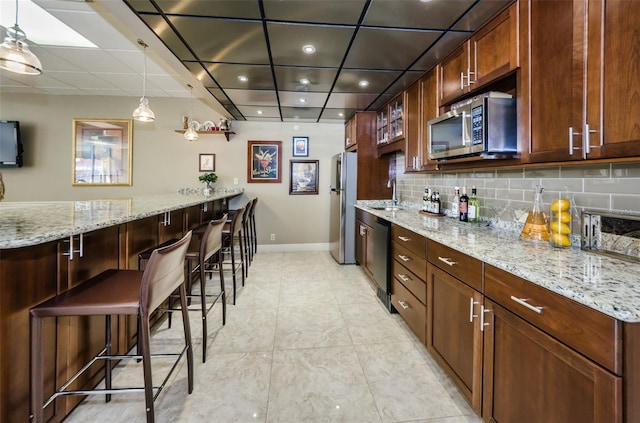 1621 Gulf Blvd Unit 407, Clearwater Beach, FL 33767 - kitchen featuring appliances with stainless steel finishes, recessed lighting, tasteful backsplash, a kitchen breakfast bar, and light stone counters