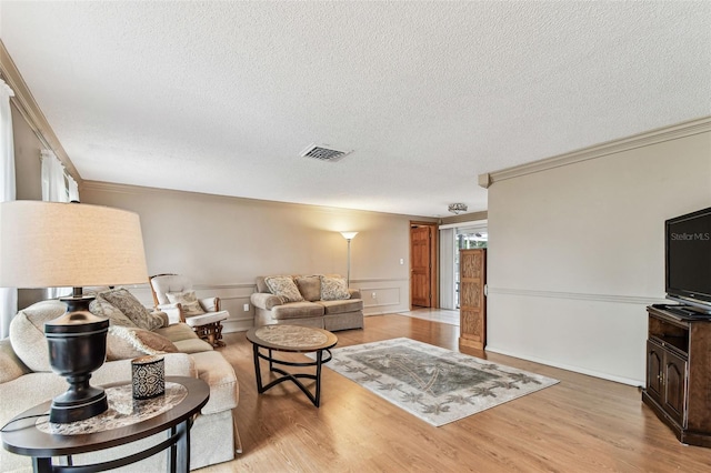 12101 Meadowbrook Ln, Hudson, FL 34667 - living area with ornamental molding, a textured ceiling, light wood-type flooring, and a wainscoted wall