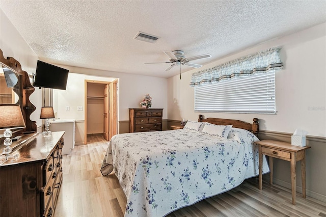 12101 Meadowbrook Ln, Hudson, FL 34667 - bedroom with light wood-style floors, a textured ceiling, a walk in closet, a ceiling fan, and a closet