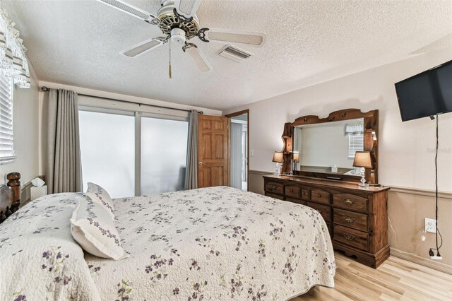 12101 Meadowbrook Ln, Hudson, FL 34667 - bedroom with light wood-type flooring, a textured ceiling, a ceiling fan, and baseboards