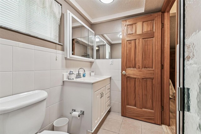 12101 Meadowbrook Ln, Hudson, FL 34667 - bathroom featuring tile walls, tile patterned floors, toilet, vanity, and a textured ceiling