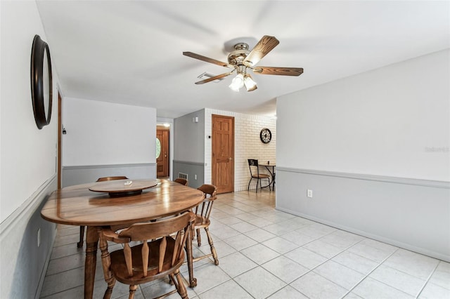 12101 Meadowbrook Ln, Hudson, FL 34667 - dining area featuring a ceiling fan, light tile patterned flooring, baseboards, and brick wall