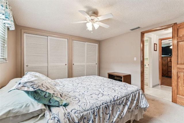 12101 Meadowbrook Ln, Hudson, FL 34667 - bedroom featuring multiple closets, light tile patterned floors, ceiling fan, light carpet, and a textured ceiling