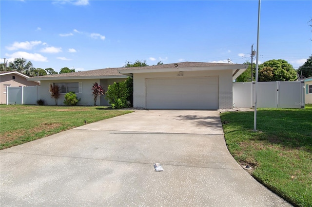 13898 Jamaica Dr, Seminole, FL 33776 - ranch-style house with brick siding, concrete driveway, an attached garage, a gate, and stucco siding