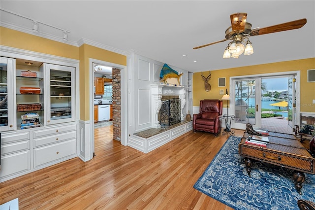 224 Harbor View Ln, Largo, FL 33770 - living room featuring light wood-style floors, track lighting, a fireplace with raised hearth, ceiling fan, and crown molding
