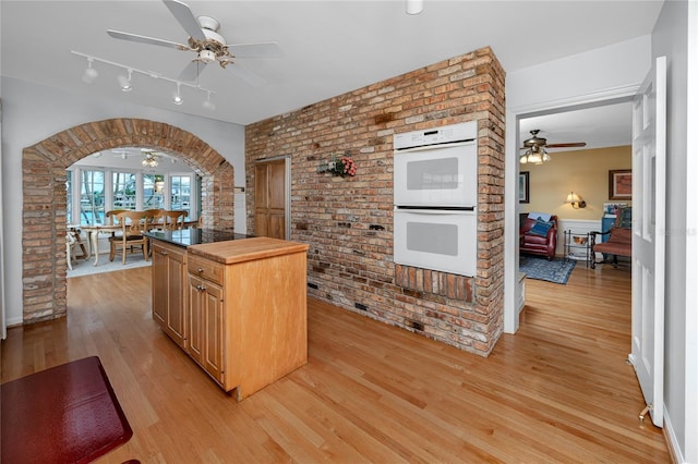 224 Harbor View Ln, Largo, FL 33770 - kitchen with a ceiling fan, double oven, brick wall, wood counters, and light wood-style flooring