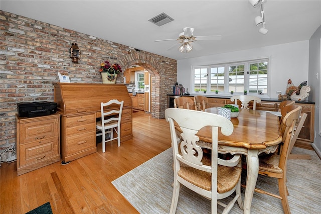 224 Harbor View Ln, Largo, FL 33770 - dining room featuring brick wall, arched walkways, plenty of natural light, and light wood-style floors