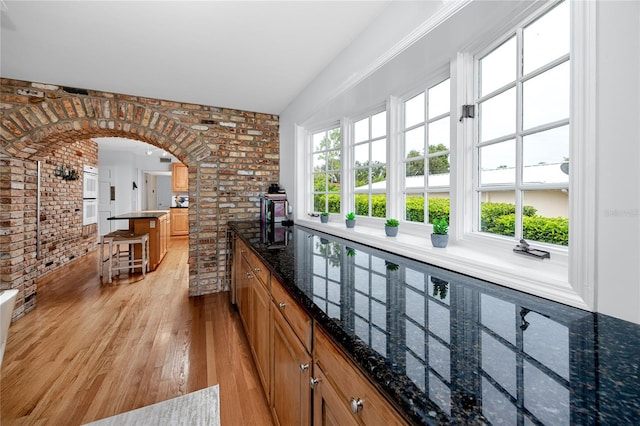 224 Harbor View Ln, Largo, FL 33770 - bar area featuring brick wall, arched walkways, light wood finished floors, and white double oven