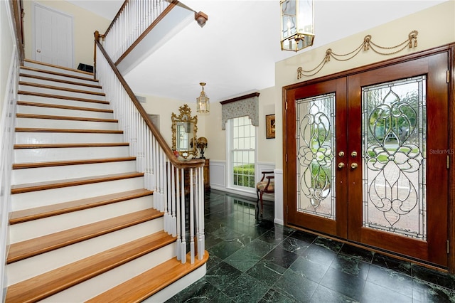 224 Harbor View Ln, Largo, FL 33770 - foyer entrance with stairs, french doors, wainscoting, a chandelier, and a decorative wall