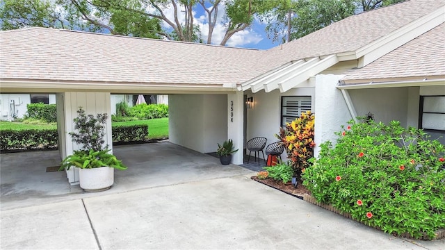 3504 Wedge Way, New Port Richey, FL 34655 - property entrance with a shingled roof, a carport, concrete driveway, and stucco siding
