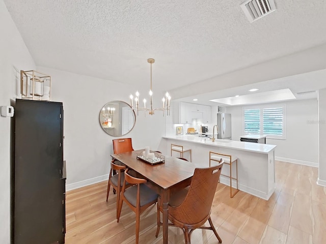 3504 Wedge Way, New Port Richey, FL 34655 - dining room with light wood-style floors, a chandelier, and a textured ceiling