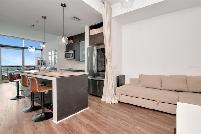 111 N 12th St Unit 1805, Tampa, FL 33602 - kitchen featuring appliances with stainless steel finishes, a kitchen breakfast bar, a center island, light countertops, and light wood finished floors