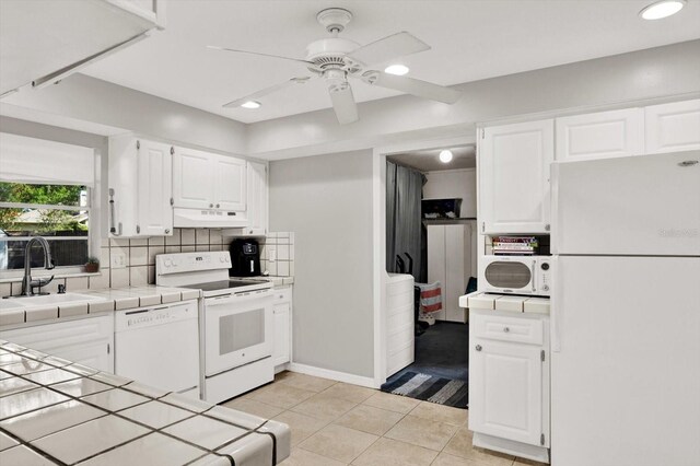 3615 Greatwood Ct, Land O Lakes, FL 34639 - kitchen featuring white appliances, tile counters, under cabinet range hood, a sink, and white cabinets