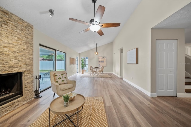4509 Grainary Ave, Tampa, FL 33624 - living room featuring lofted ceiling, a ceiling fan, light wood-style floors, a stone fireplace, and baseboards