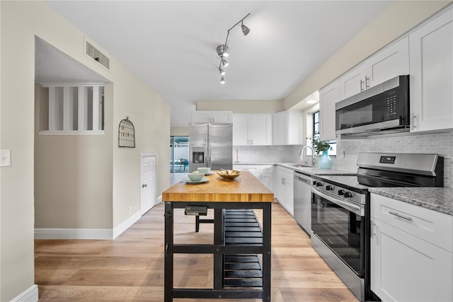 4509 Grainary Ave, Tampa, FL 33624 - kitchen featuring appliances with stainless steel finishes, a sink, white cabinetry, and decorative backsplash