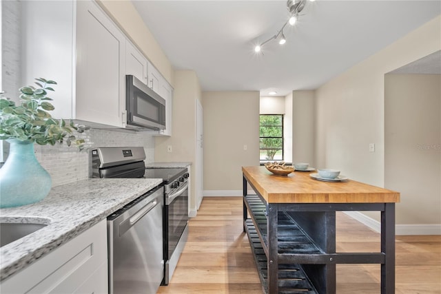 4509 Grainary Ave, Tampa, FL 33624 - kitchen featuring appliances with stainless steel finishes, backsplash, white cabinetry, and baseboards