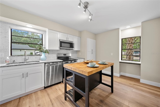 4509 Grainary Ave, Tampa, FL 33624 - kitchen featuring stainless steel appliances, a sink, decorative backsplash, baseboards, and white cabinetry