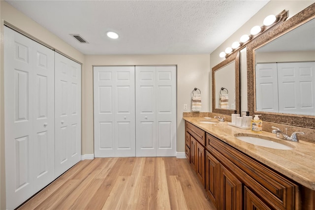 4509 Grainary Ave, Tampa, FL 33624 - bathroom featuring a closet, double vanity, wood finished floors, baseboards, and a textured ceiling