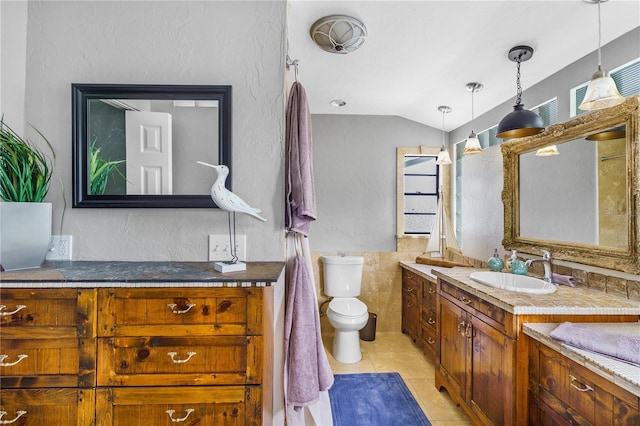 4916 Palmetto Point Dr, Palmetto, FL 34221 - bathroom with tile walls, two vanities, tile patterned flooring, toilet, and lofted ceiling