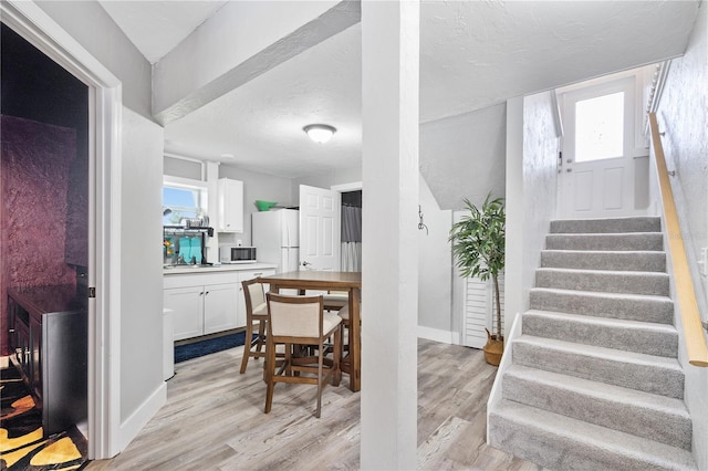 4916 Palmetto Point Dr, Palmetto, FL 34221 - dining space with light wood finished floors, stairs, a textured ceiling, and baseboards