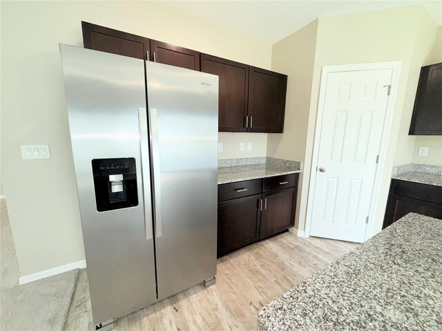 13118 Zolo Springs Cir, Riverview, FL 33579 - kitchen with stainless steel fridge with ice dispenser, light wood finished floors, dark brown cabinets, and light stone counters