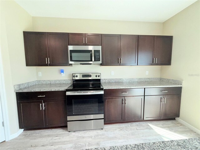 13118 Zolo Springs Cir, Riverview, FL 33579 - kitchen with stainless steel appliances, dark brown cabinets, light countertops, and light wood finished floors