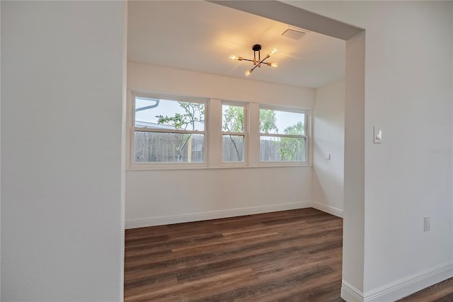 410 Virginia Ave, Madeira Beach, FL 33708 - unfurnished room with a chandelier, dark wood-type flooring, and baseboards