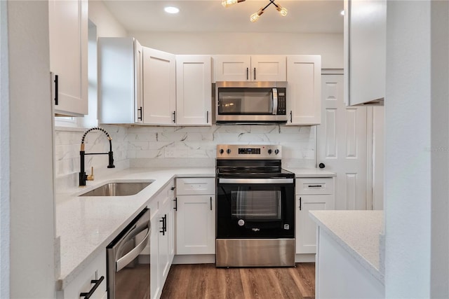 410 Virginia Ave, Madeira Beach, FL 33708 - kitchen featuring appliances with stainless steel finishes, a sink, wood finished floors, white cabinets, and recessed lighting