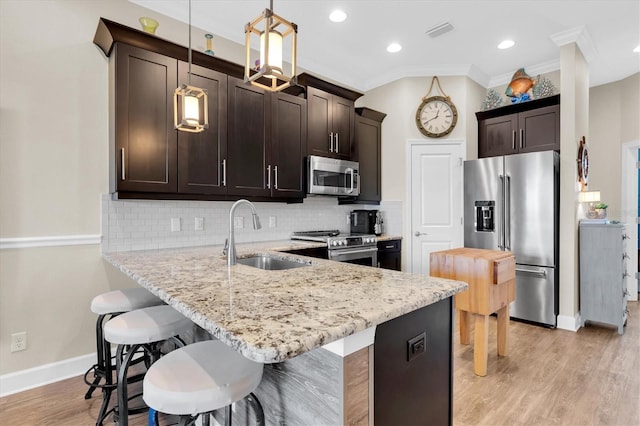 204 Haven Beach Ct, Indian Rocks Beach, FL 33785 - kitchen with appliances with stainless steel finishes, dark brown cabinetry, a kitchen bar, a peninsula, and light stone counters