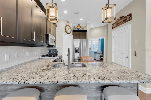 204 Haven Beach Ct, Indian Rocks Beach, FL 33785 - kitchen featuring stainless steel appliances, dark brown cabinets, decorative backsplash, light stone countertops, and crown molding