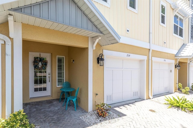 204 Haven Beach Ct, Indian Rocks Beach, FL 33785 - property entrance with board and batten siding, a garage, stucco siding, and driveway