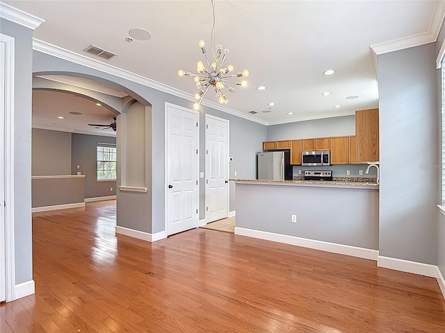 3111 W De Leon St Unit 2, Tampa, FL 33609 - kitchen featuring appliances with stainless steel finishes, arched walkways, brown cabinetry, light wood-type flooring, and a peninsula