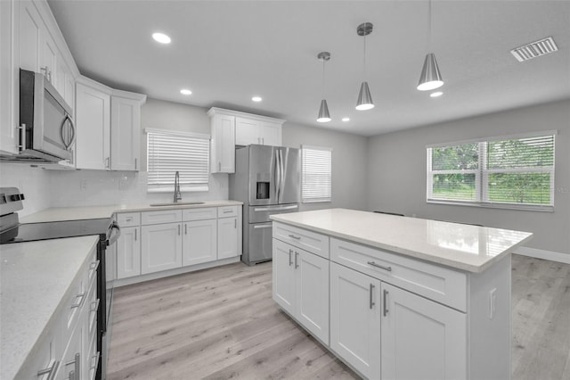 2307 N 47th St, Tampa, FL 33605 - kitchen with stainless steel appliances, a sink, light wood finished floors, recessed lighting, and white cabinets