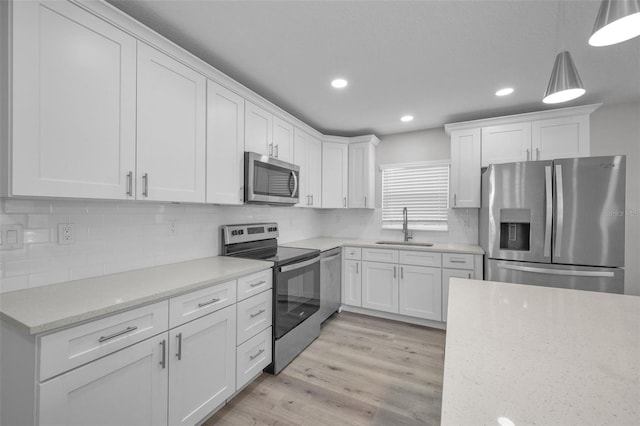 2307 N 47th St, Tampa, FL 33605 - kitchen with appliances with stainless steel finishes, a sink, white cabinetry, light wood-style floors, and tasteful backsplash