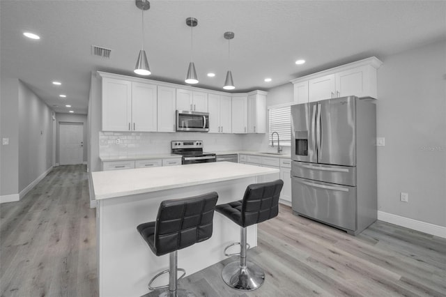 2307 N 47th St, Tampa, FL 33605 - kitchen featuring stainless steel appliances, a sink, baseboards, light countertops, and white cabinetry